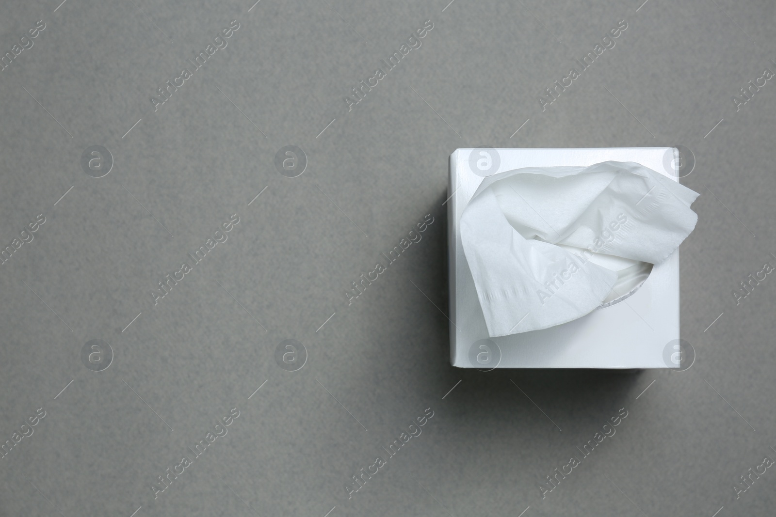 Photo of Box of paper tissues on grey background, top view. Space for text