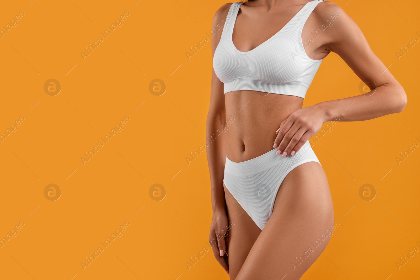 Photo of Young woman in stylish white bikini on orange background, closeup. Space for text
