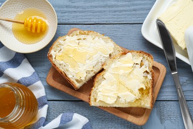 Slices of bread with butter and honey on grey wooden table, flat lay