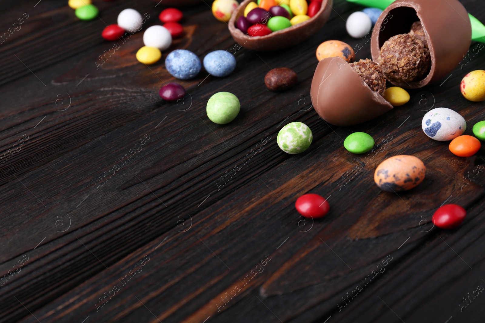 Photo of Tasty chocolate eggs and sweets on wooden table. Space for text