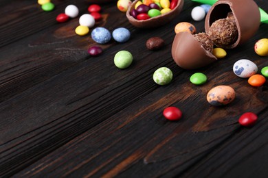 Tasty chocolate eggs and sweets on wooden table. Space for text
