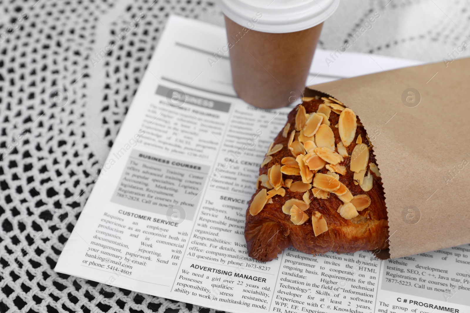 Photo of Delicious croissant and paper cup of coffee on table, closeup. Space for text