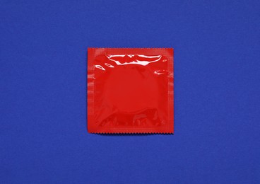 Photo of Condom package on blue background, top view. Safe sex