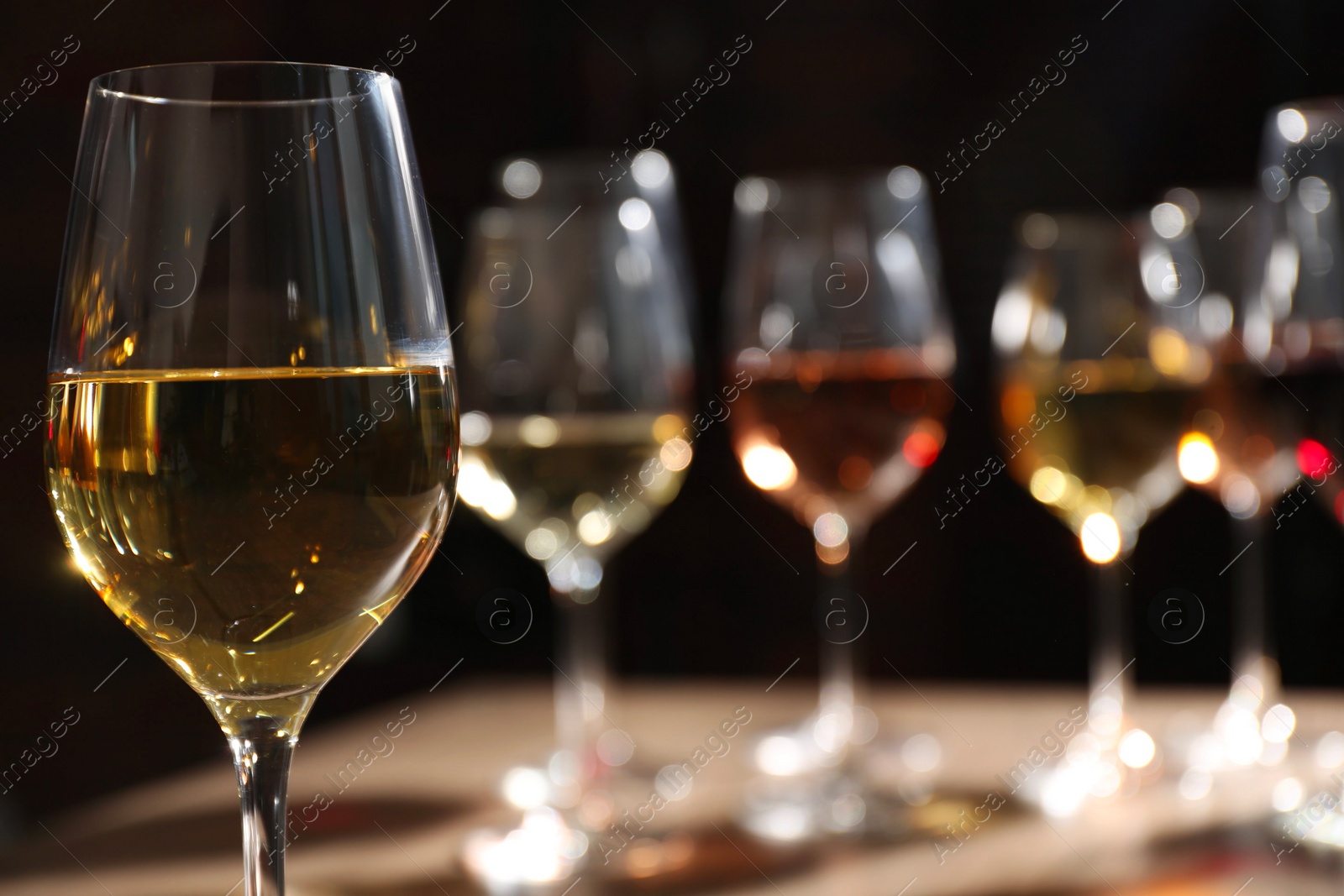 Photo of Tasty white wine in glass against blurred background, space for text