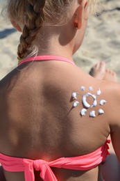 Little girl with sun protection cream on body outdoors, closeup