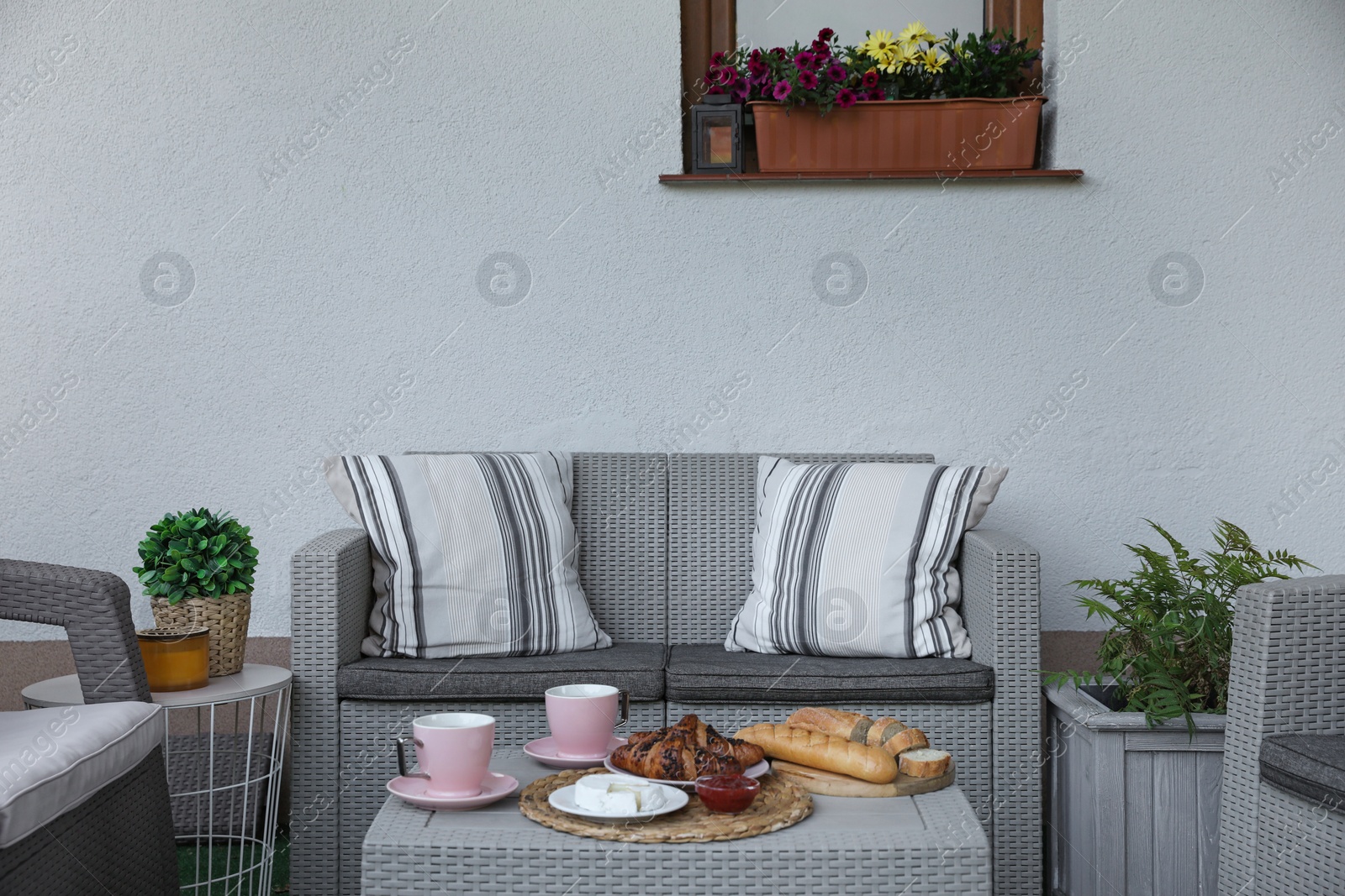 Outdoor breakfast with tea and croissants on rattan table on terrace Photo of Outdoor breakfast with tea and croissants on rattan table on terrace