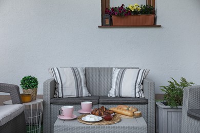 Photo of Outdoor breakfast with tea and croissants on rattan table on terrace