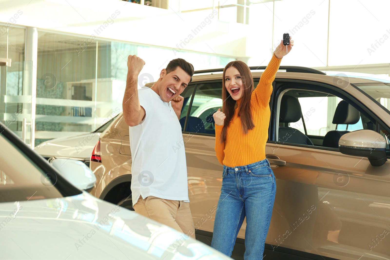 Photo of Happy couple with car key in modern auto dealership