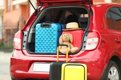 Photo of Suitcases, toy and hat in car trunk, closeup