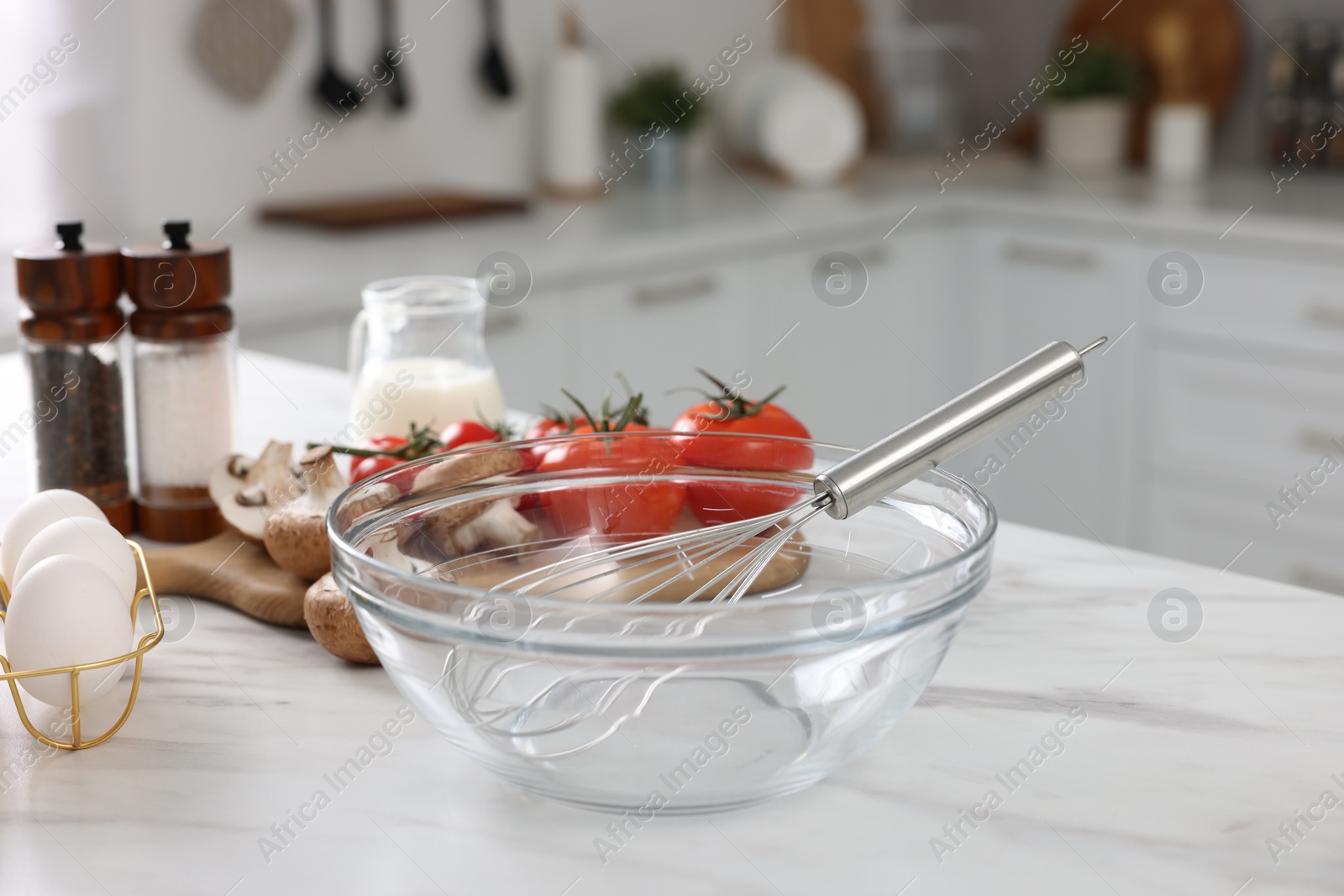 Photo of Whisk, bowl, and different ingredients on white marble table indoors