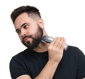 Photo of Handsome young man trimming beard on white background