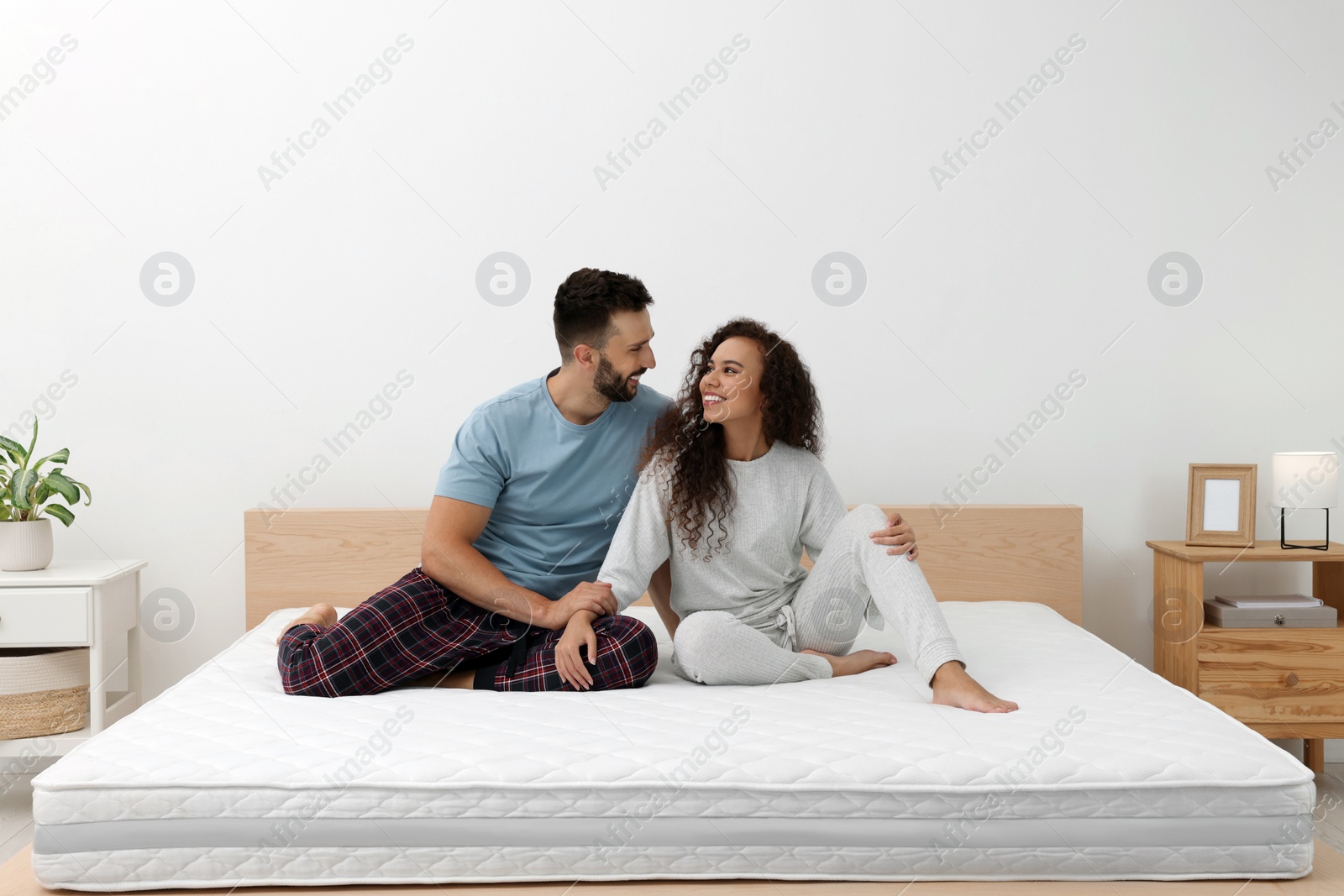 Photo of Happy couple on bed with comfortable mattress at home