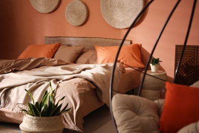 Photo of Bed with orange and brown linens in stylish room interior