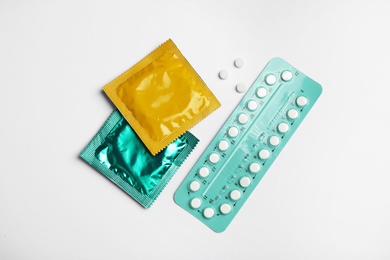 Photo of Condoms and birth control pills on light grey background, flat lay. Safe sex concept