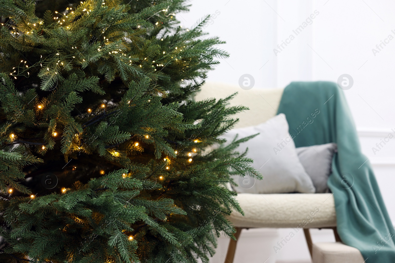 Photo of Beautiful Christmas tree decorated with festive lights in living room, closeup. Space for text