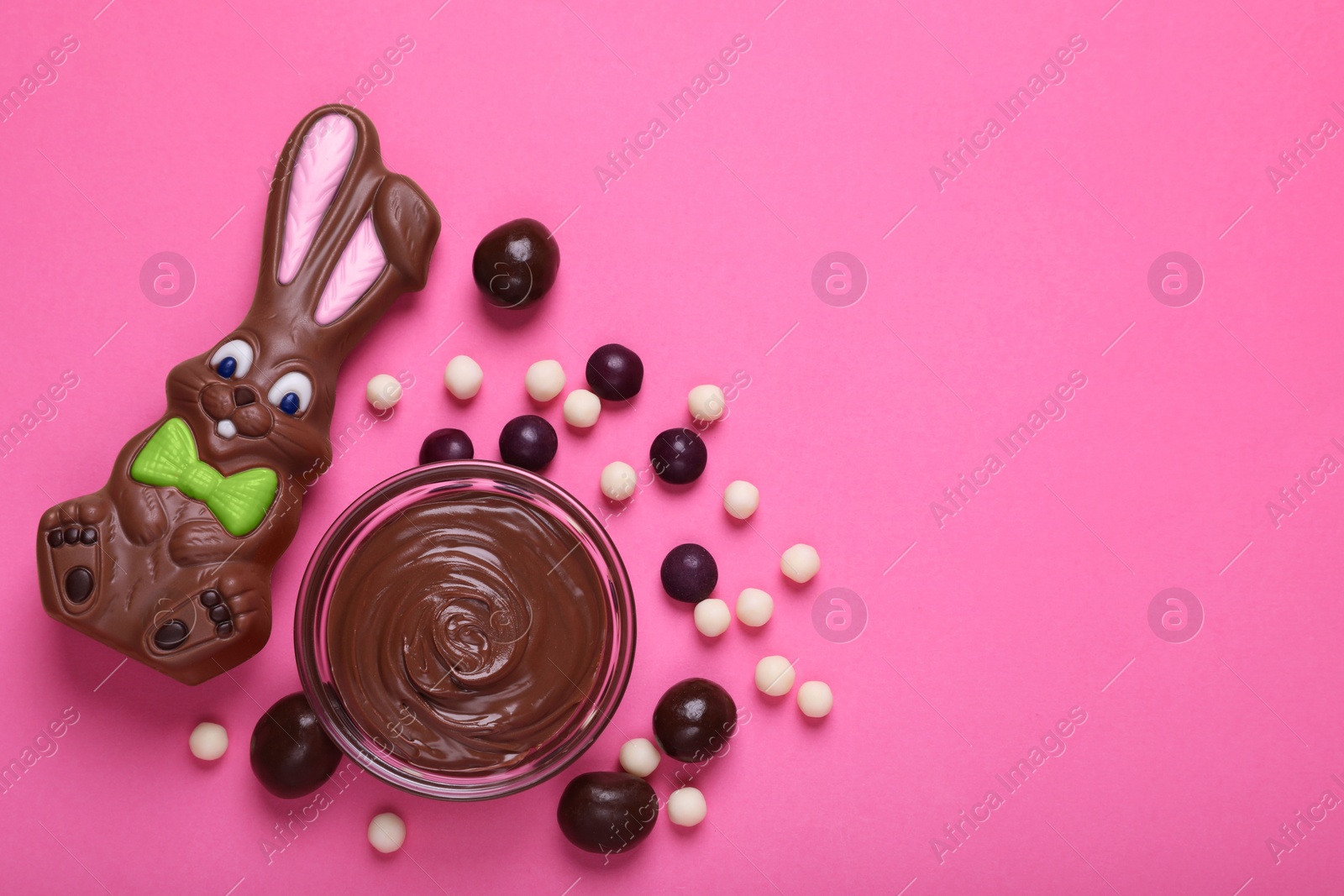 Photo of Flat lay composition with chocolate Easter bunny and candies on pink background. Space for text