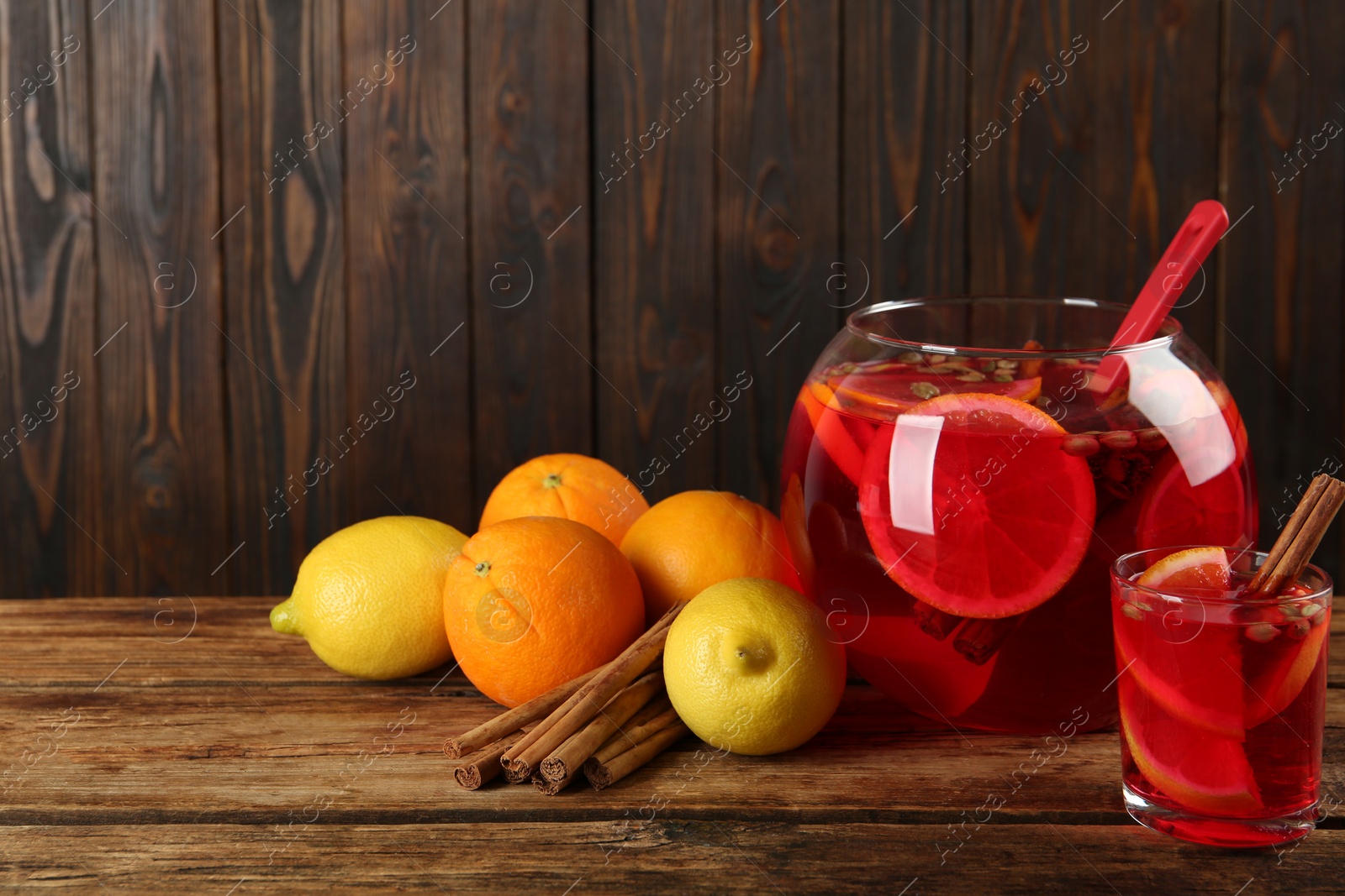 Photo of Aromatic punch drink and ingredients on wooden table, space for text