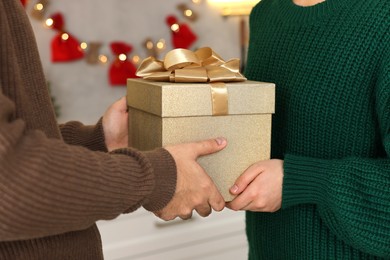 Photo of Man presenting Christmas gift to his girlfriend at home, closeup