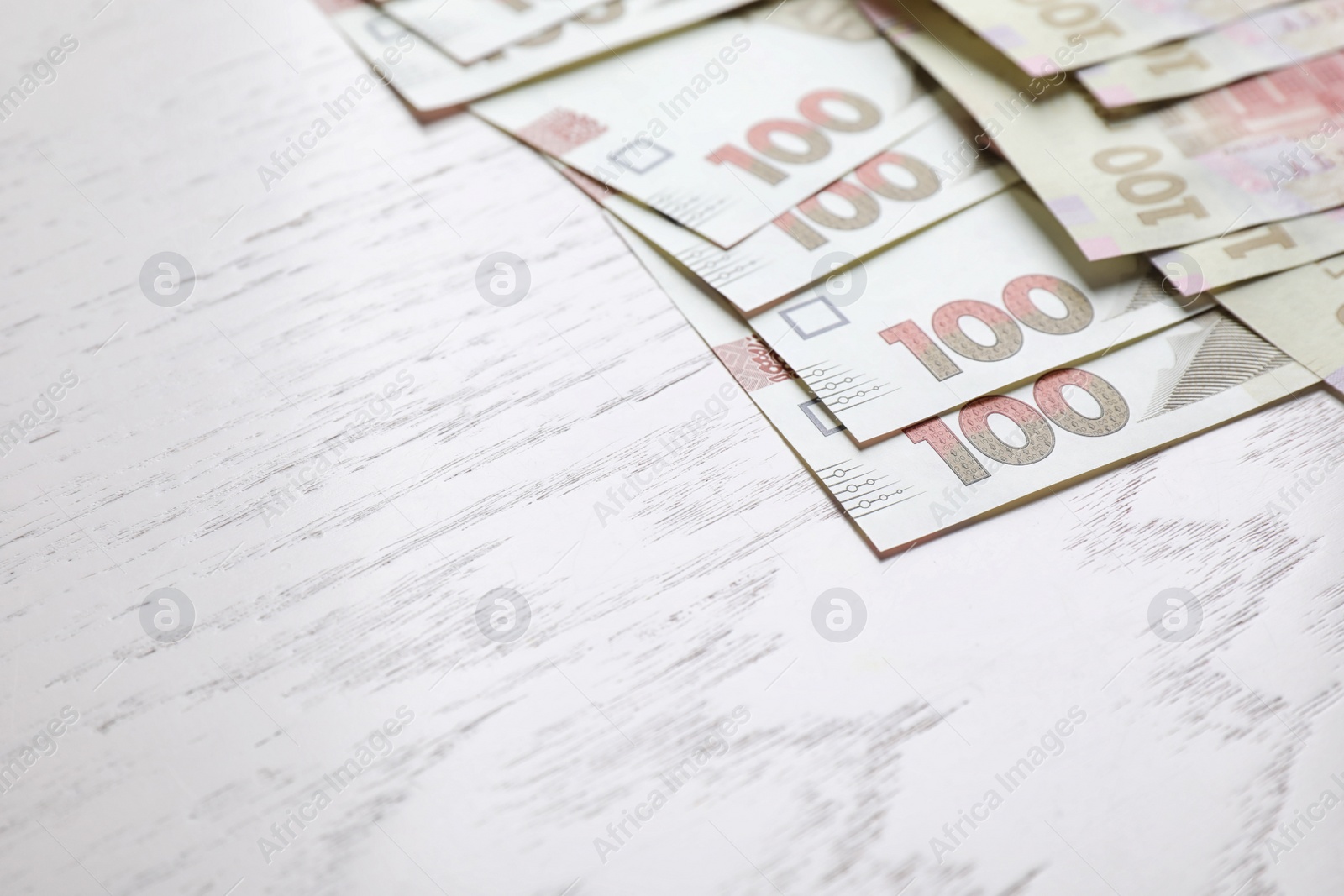 Photo of Ukrainian money on white wooden background, closeup. Space for text