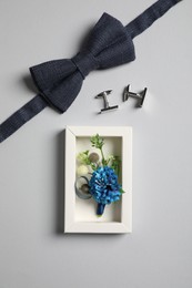 Wedding stuff. Stylish boutonniere, bow tie and cufflinks on gray background, flat lay