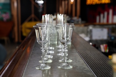 Photo of Different empty clean glasses on counter in bar