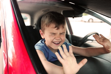 Crying little boy closed inside car. Child in danger