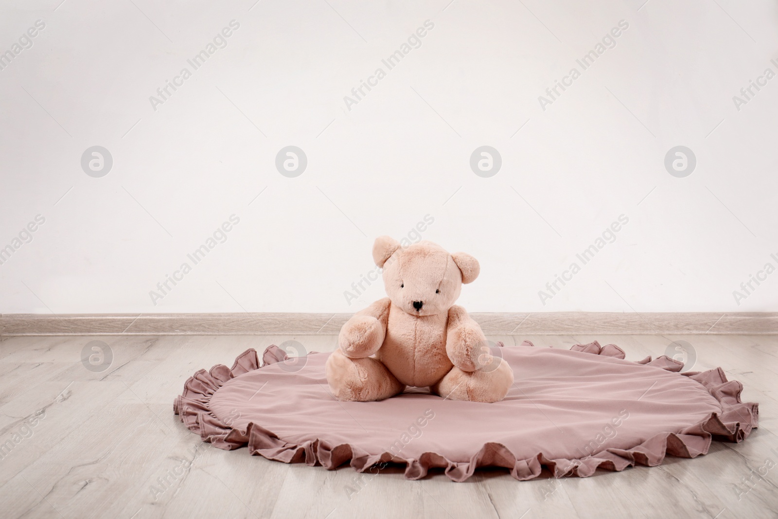 Photo of Teddy bear and rug on floor in child room. Space for text