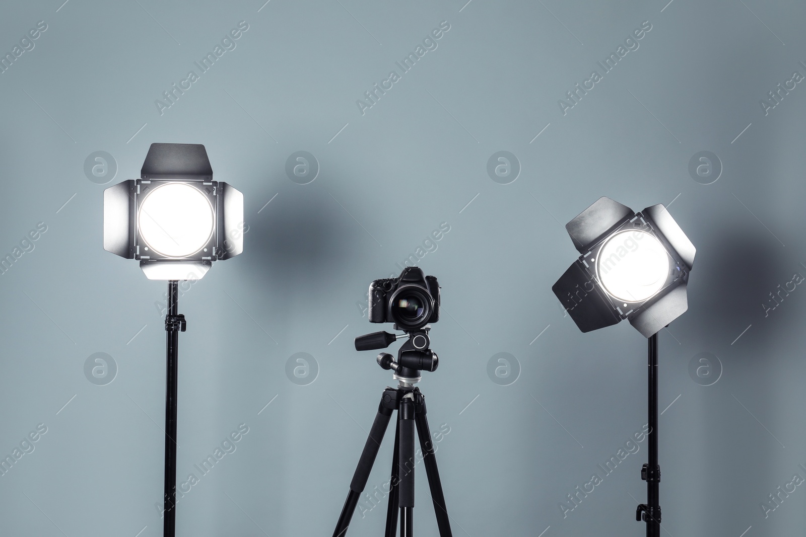 Photo of Professional video camera and lighting equipment on grey background