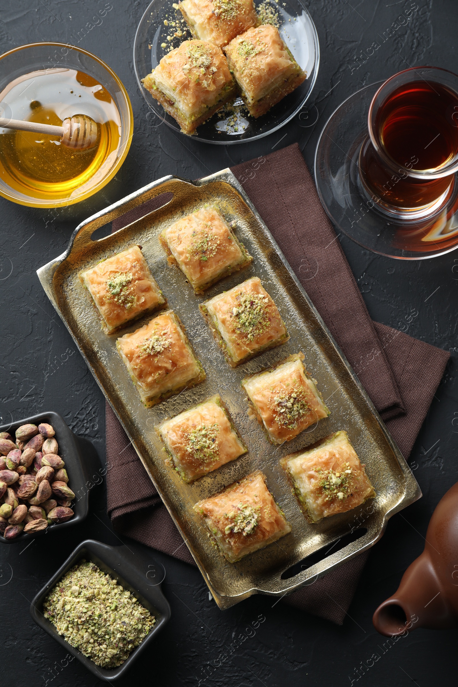 Photo of Delicious fresh baklava with chopped nuts served on grey textured table, flat lay. Eastern sweets