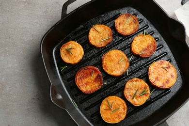 Grill pan with sweet potato fries on grey background, top view