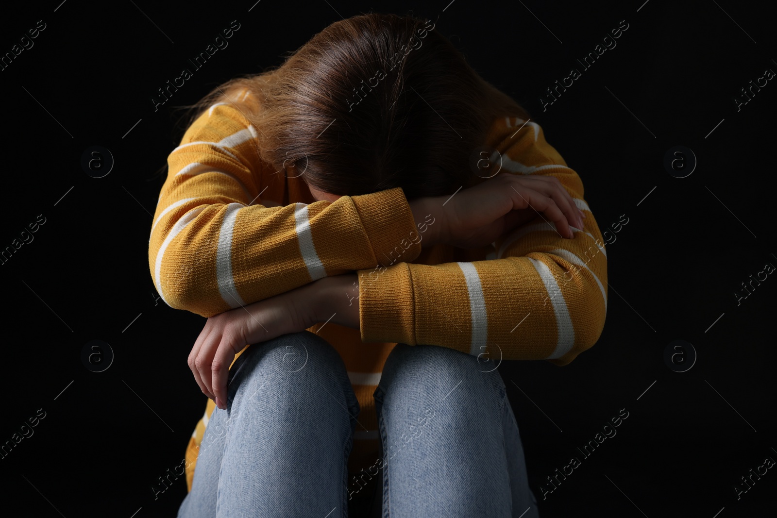 Photo of Sadness. Upset woman sitting on black background