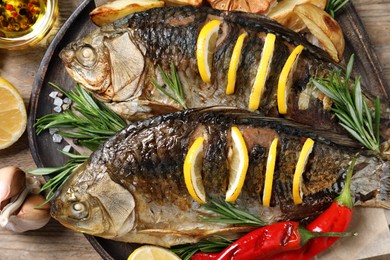 Photo of Tasty homemade roasted crucian carps served on wooden table, flat lay. River fish