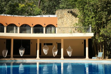 Hotel building with hammocks and clean pool outdoors