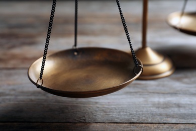 Scales of justice on wooden table, closeup. Law concept