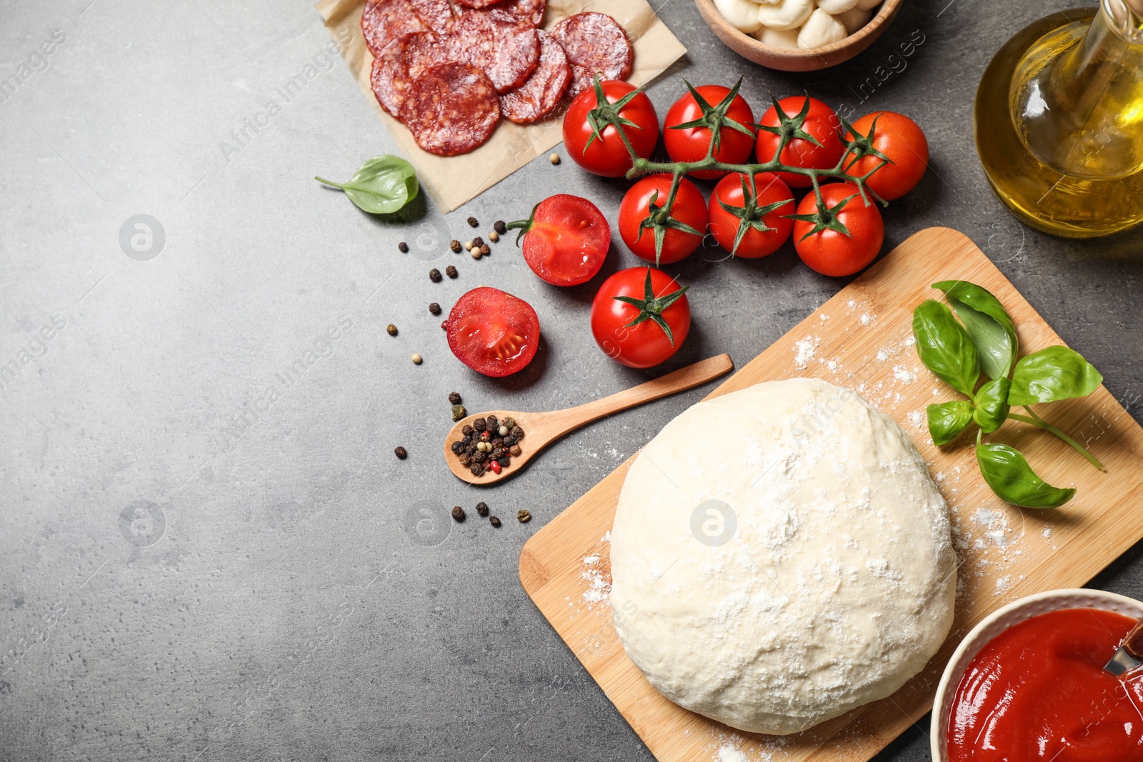 Photo of Flat lay composition with dough and ingredients on grey table, space for text. Pepperoni pizza recipe