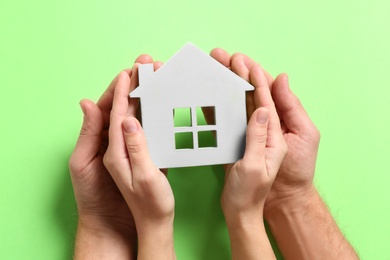 Photo of Couple holding house model on light green background, top view