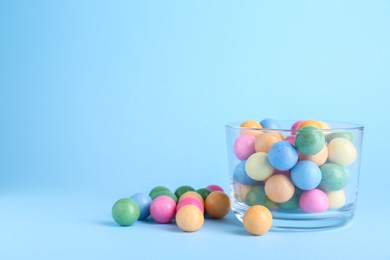 Photo of Bowl with bright gumballs on light blue background. Space for text