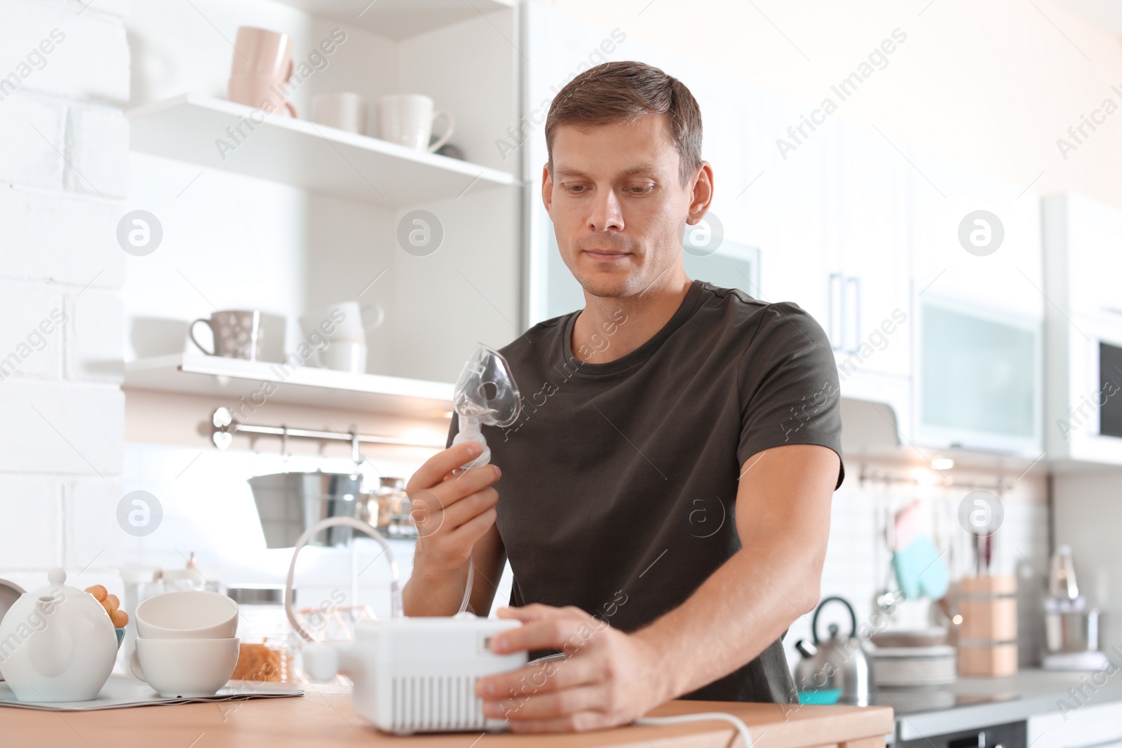 Photo of Man using asthma machine at table in kitchen