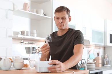 Man using asthma machine at table in kitchen