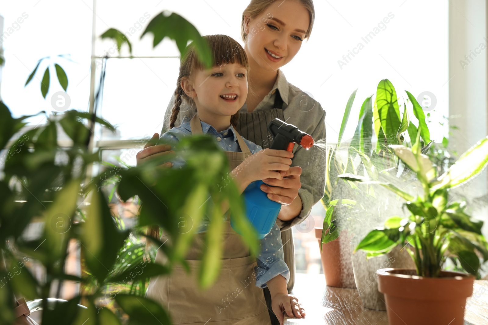Photo of Mother and daughter taking care of home plants indoors