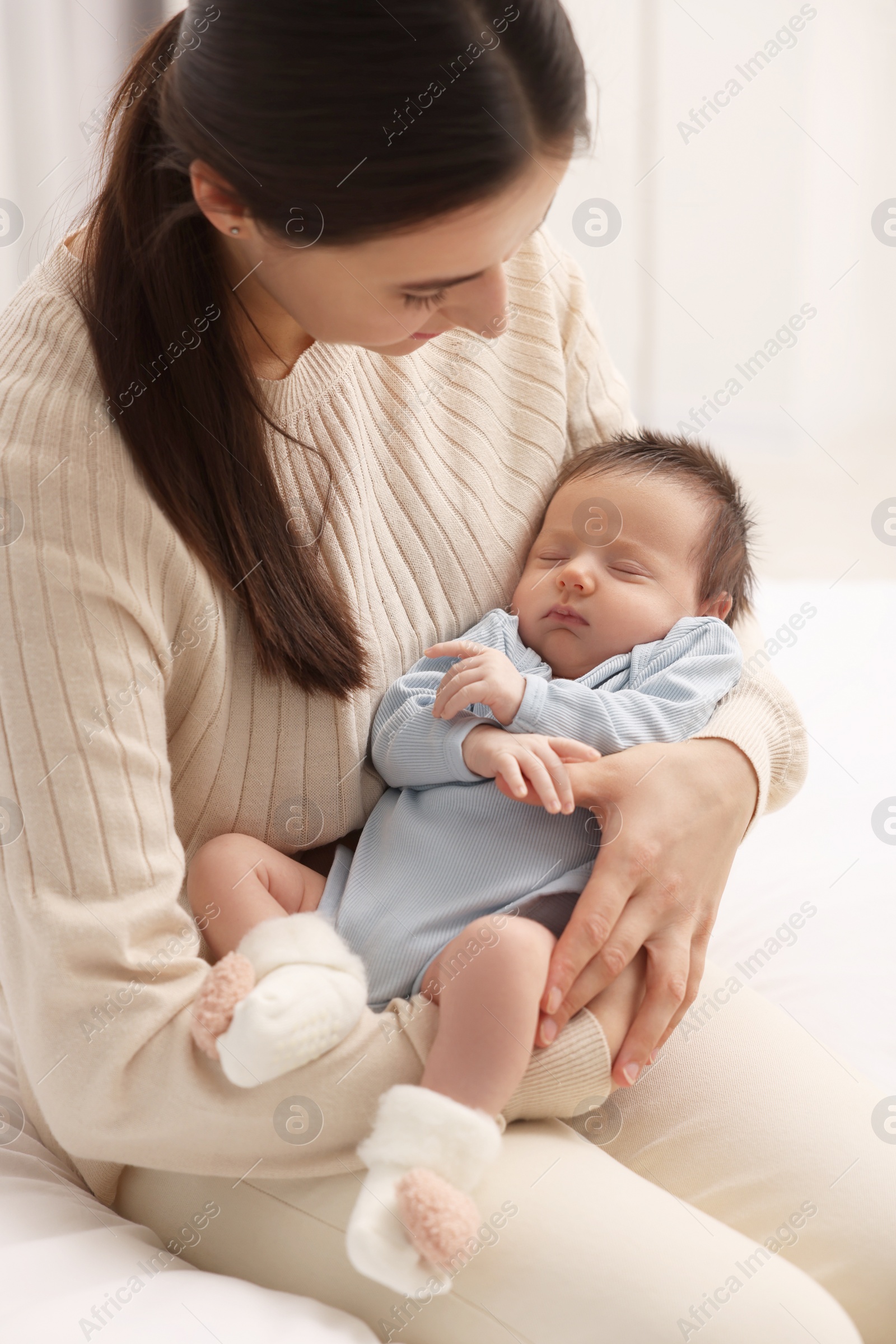 Photo of Mother with her sleeping newborn baby indoors