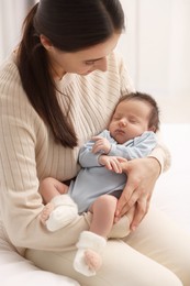 Mother with her sleeping newborn baby indoors