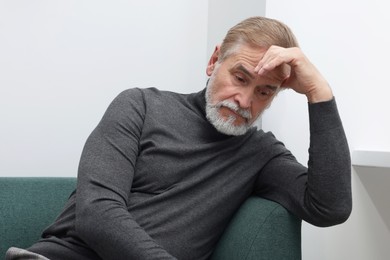 Photo of Upset senior man on sofa at home. Loneliness concept