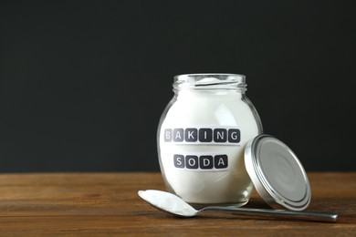 Photo of Jar and spoon with baking soda on wooden table. Space for text