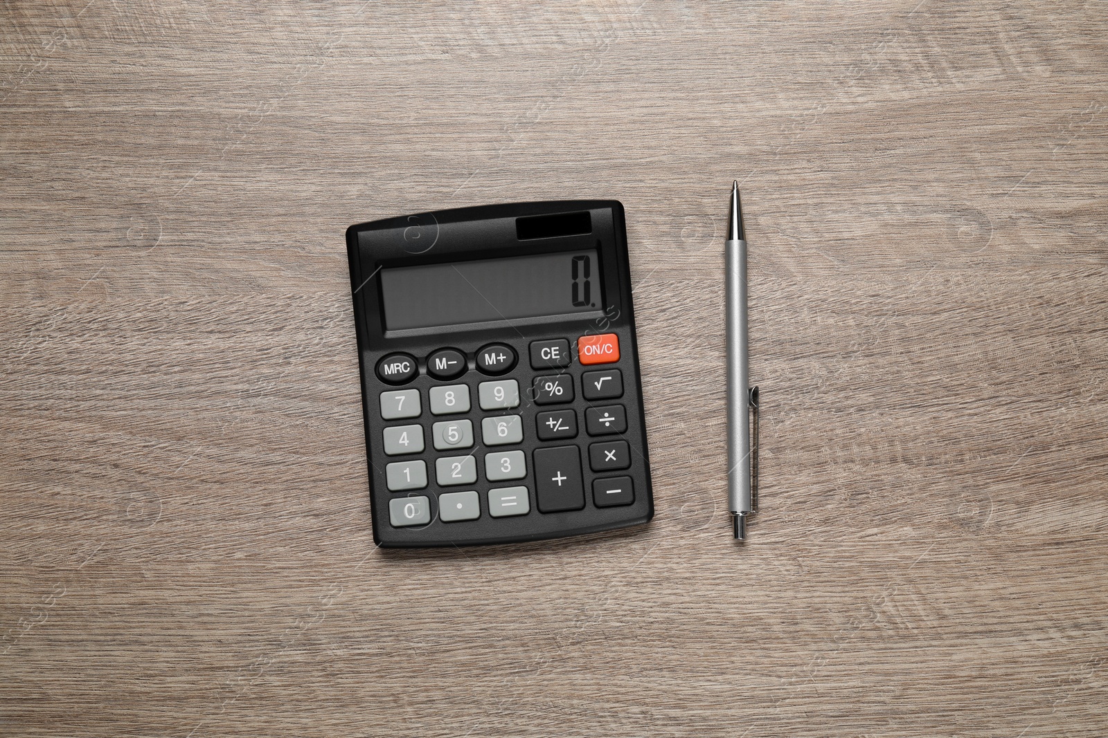 Photo of Calculator and pen on wooden table, top view