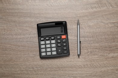 Photo of Calculator and pen on wooden table, top view