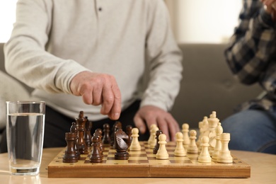 Photo of Elderly men playing chess at nursing home, closeup. Assisting senior people