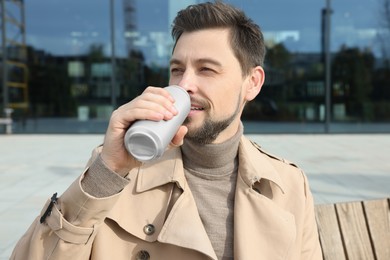 Photo of Handsome man drinking from tin can outdoors