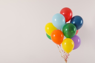 Photo of Bunch of bright balloons on light background, space for text. Celebration time