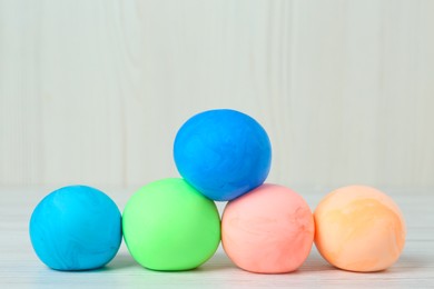 Different color play dough balls on white wooden table